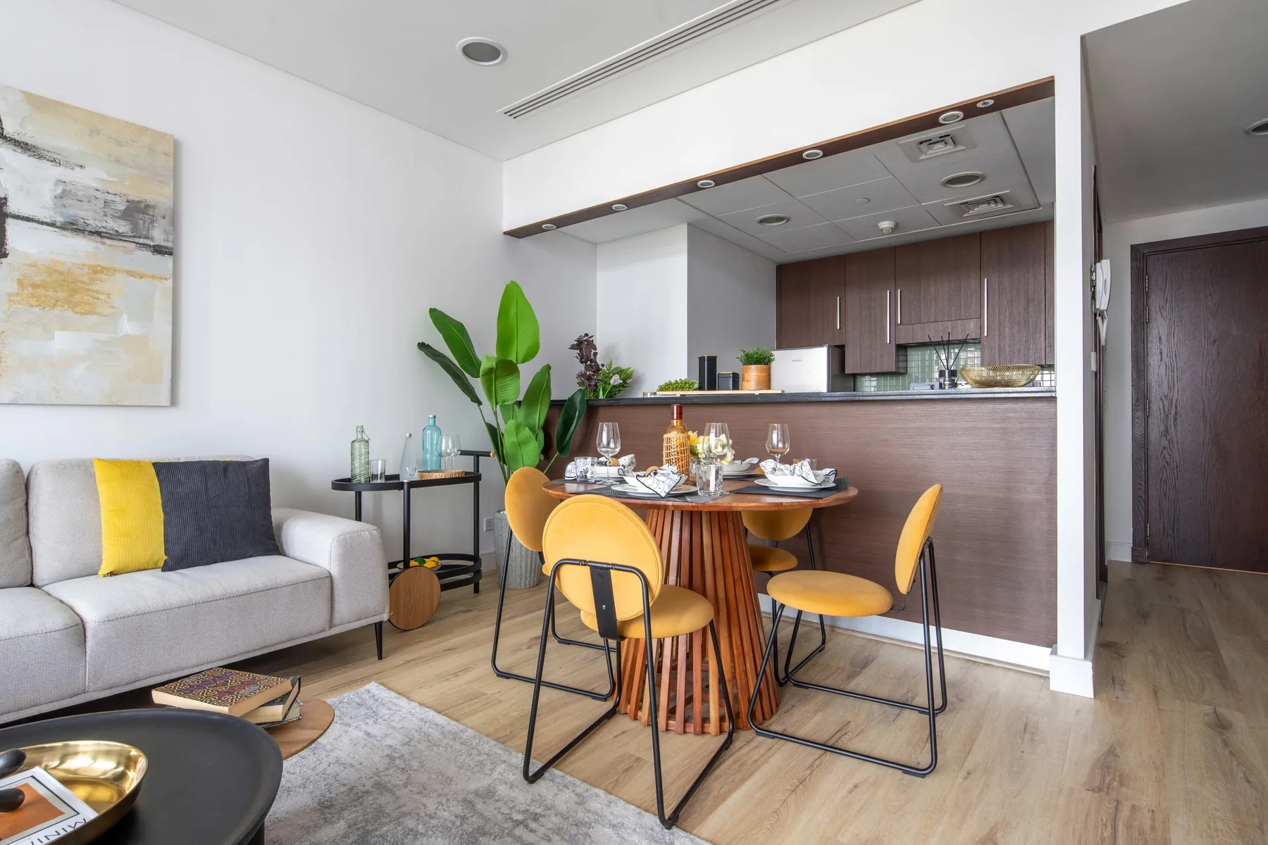 A dining area with a round table and yellow seating beside a living area.