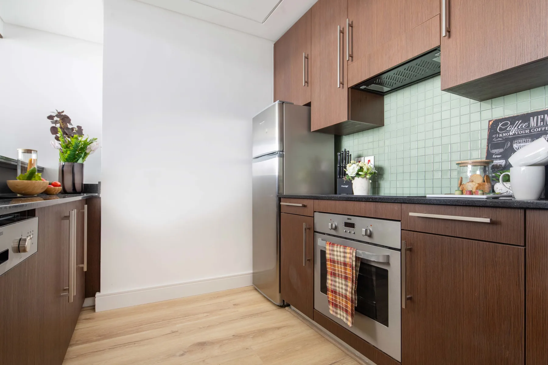 A modern kitchen with wood cabinets, stainless steel appliances, and a tiled backsplash.