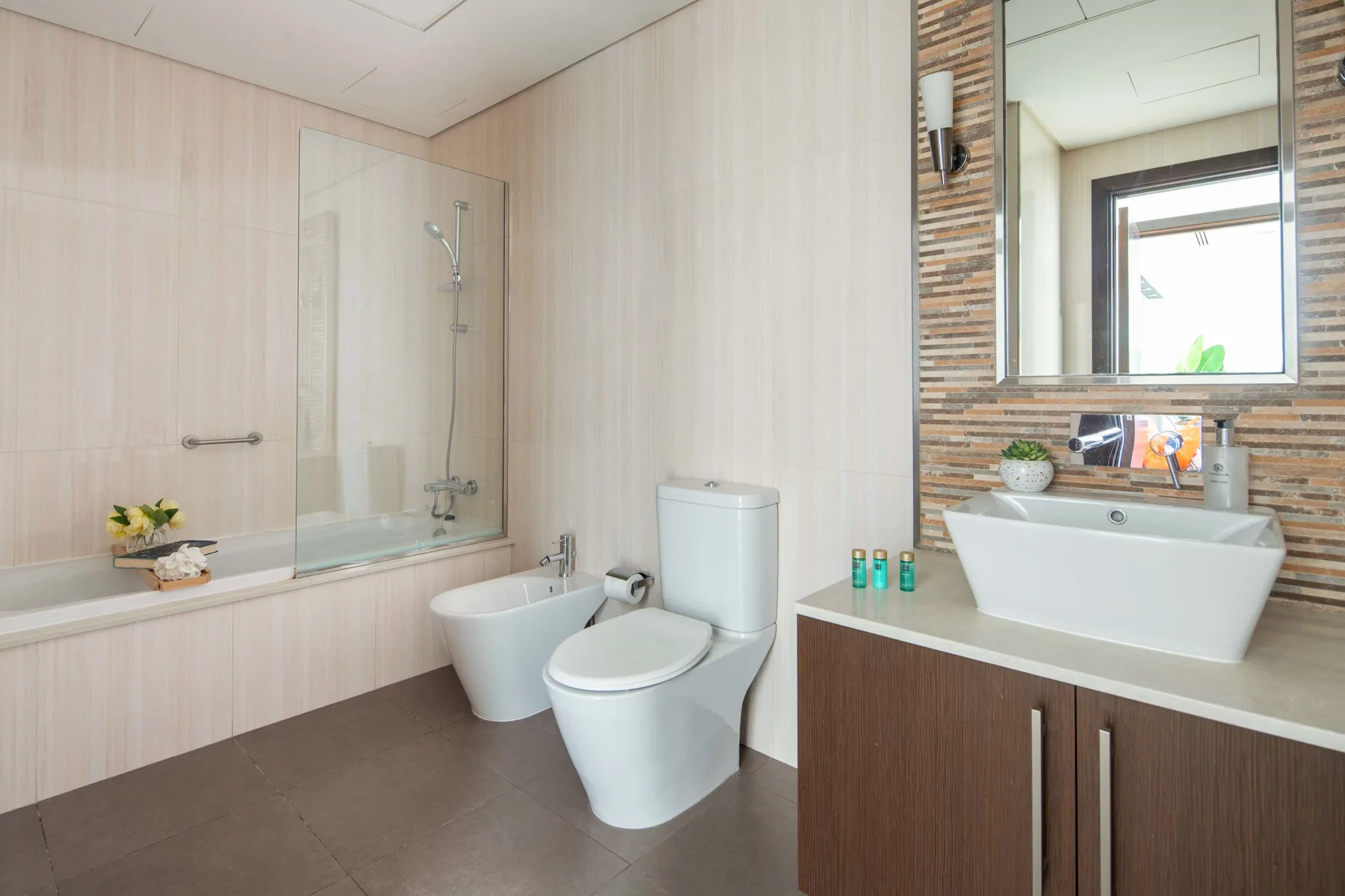 A bathroom with a bathtub, shower, toilet, and vanity with a vessel sink.