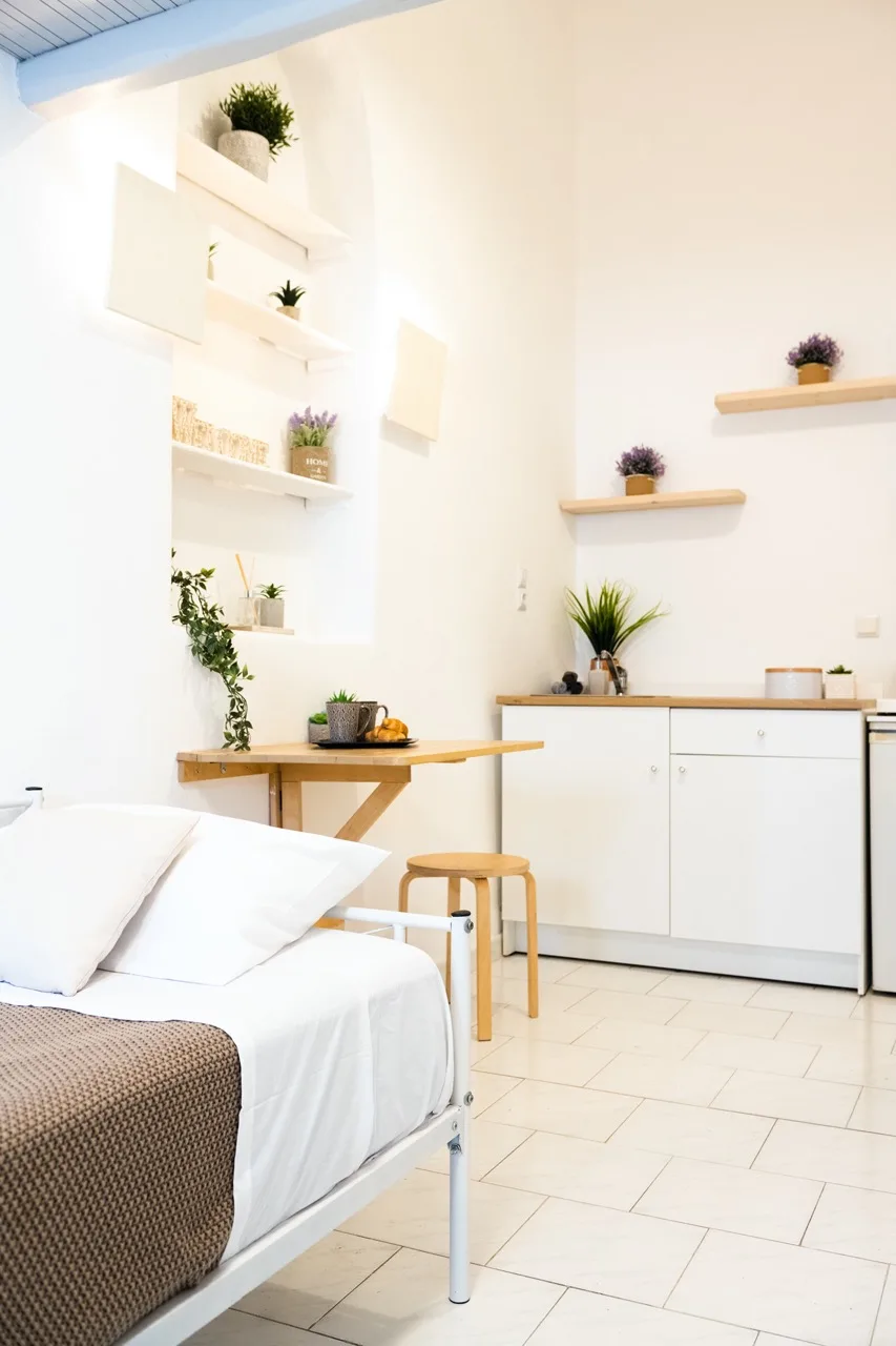 A bright bedroom with a bed, a small table, and white cabinetry.