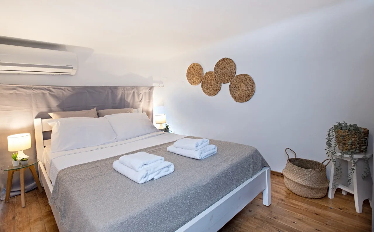 A bedroom with a double bed, neatly made with white linens and gray bedding.