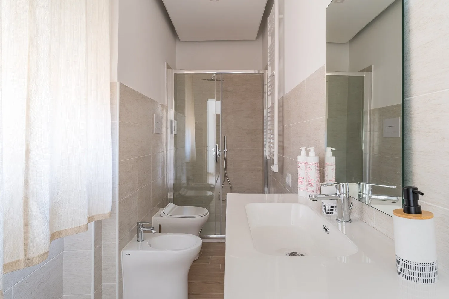 Un baño luminoso con bañera, lavabo y ducha de vidrio.