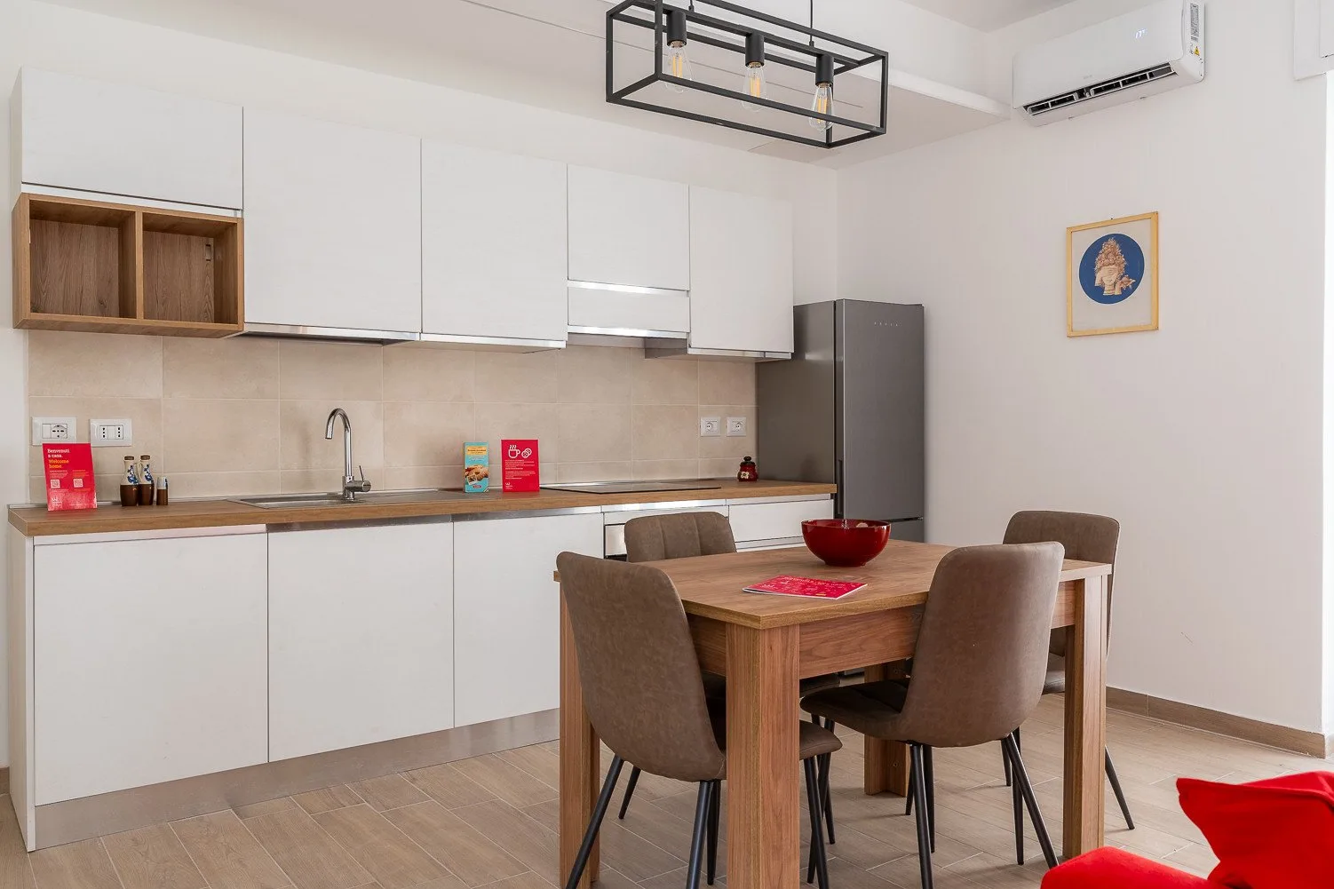 Una cocina luminosa con comedor, mesa de madera y armarios blancos.