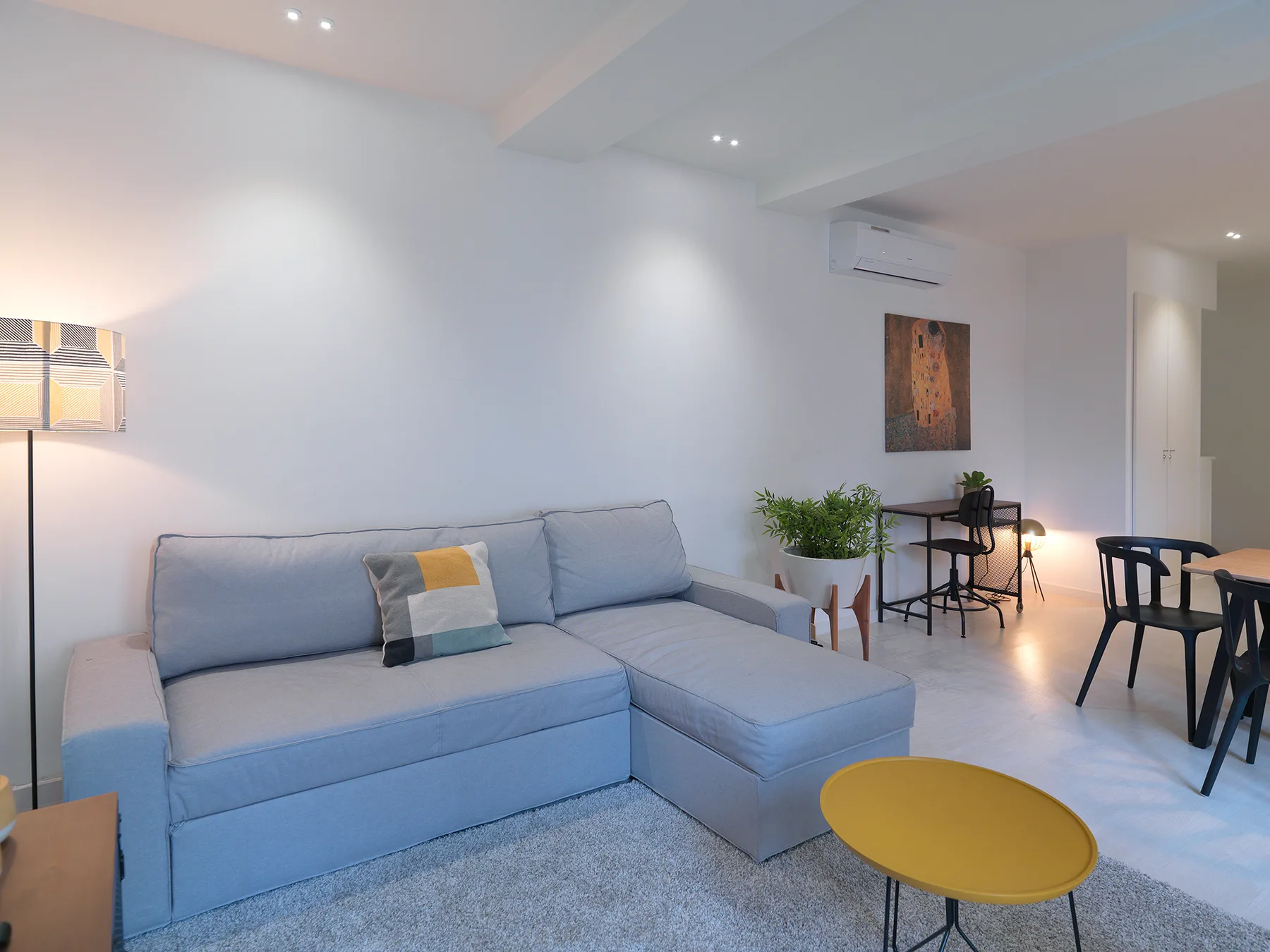 Una sala de estar con un sofá seccional claro y una mesa de centro amarilla.