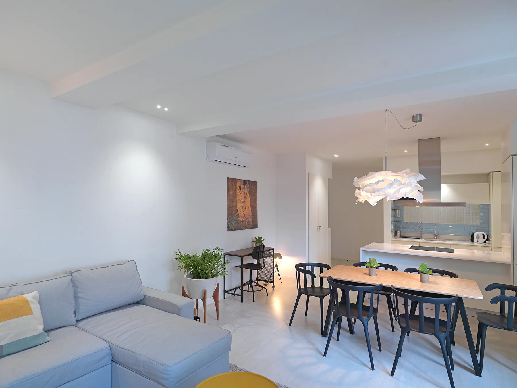 A bright apartment living and dining area with a sofa and dining table.