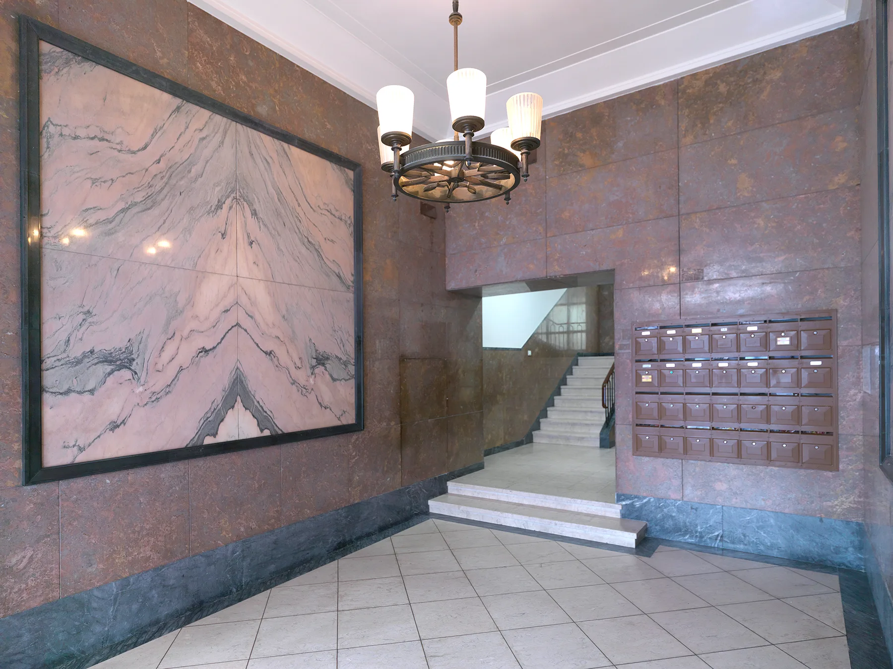 Vestíbulo de un edificio con un panel de pared jaspeado y buzones.