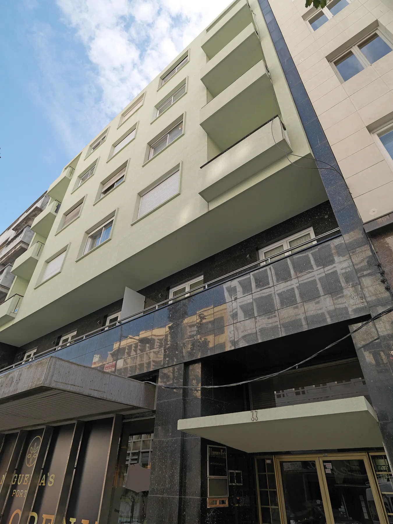 Fachada de un edificio de varias plantas con balcones sobre un local oscuro en la planta baja.