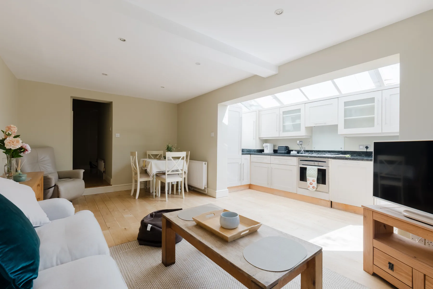 A bright open-plan living and dining area with a white kitchen.