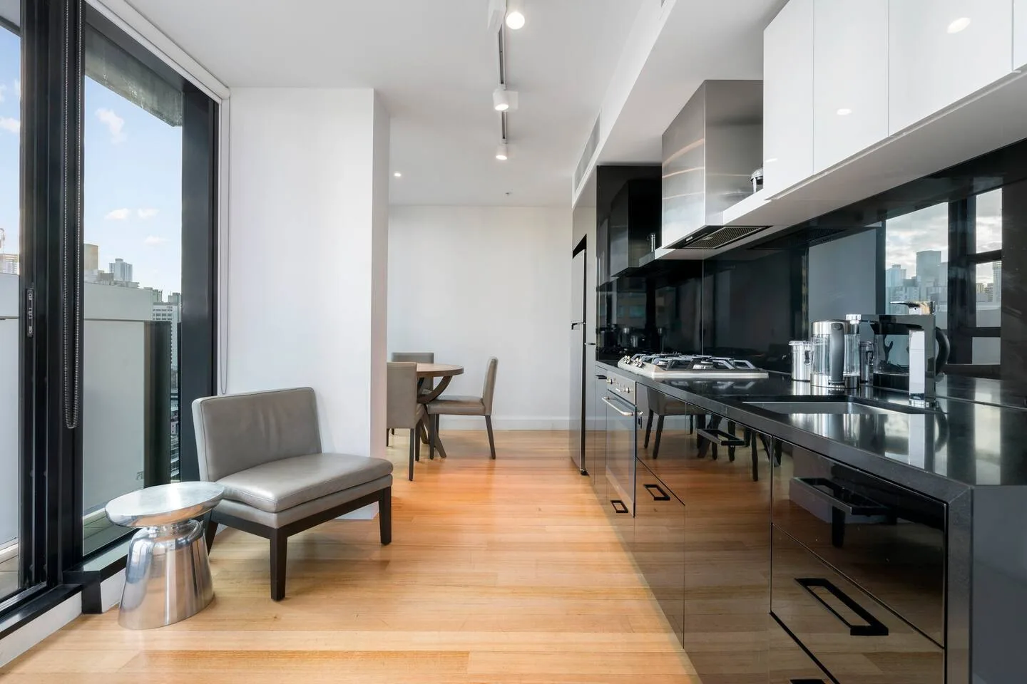 A modern kitchen with dark cabinetry and a small dining table by the windows.