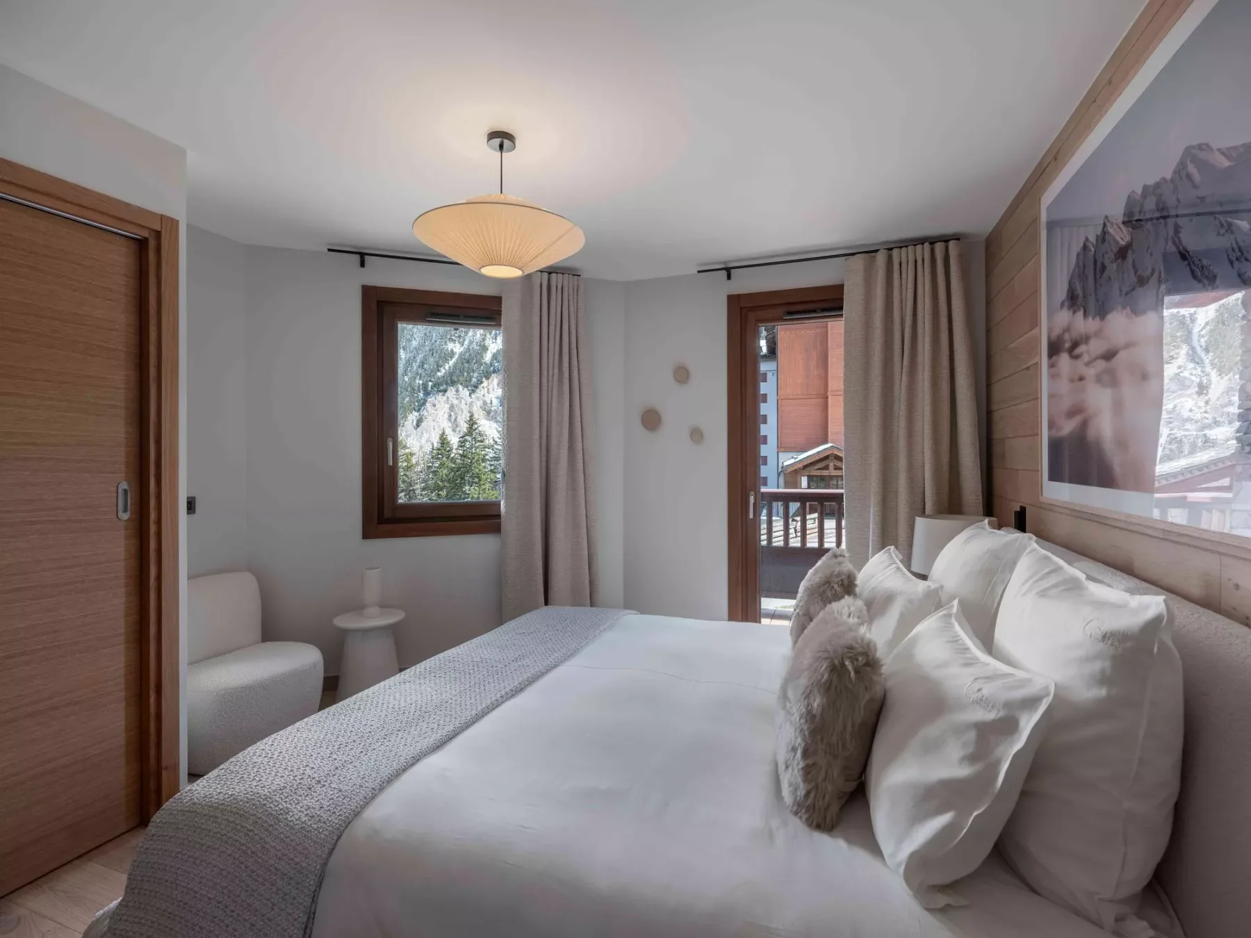 Un dormitorio con una cama bien tendida, una ventana y cortinas.