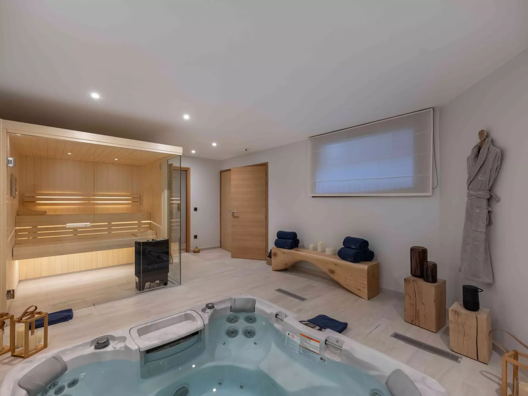 Un espacio de spa con una bañera de hidromasaje y una sauna de madera.