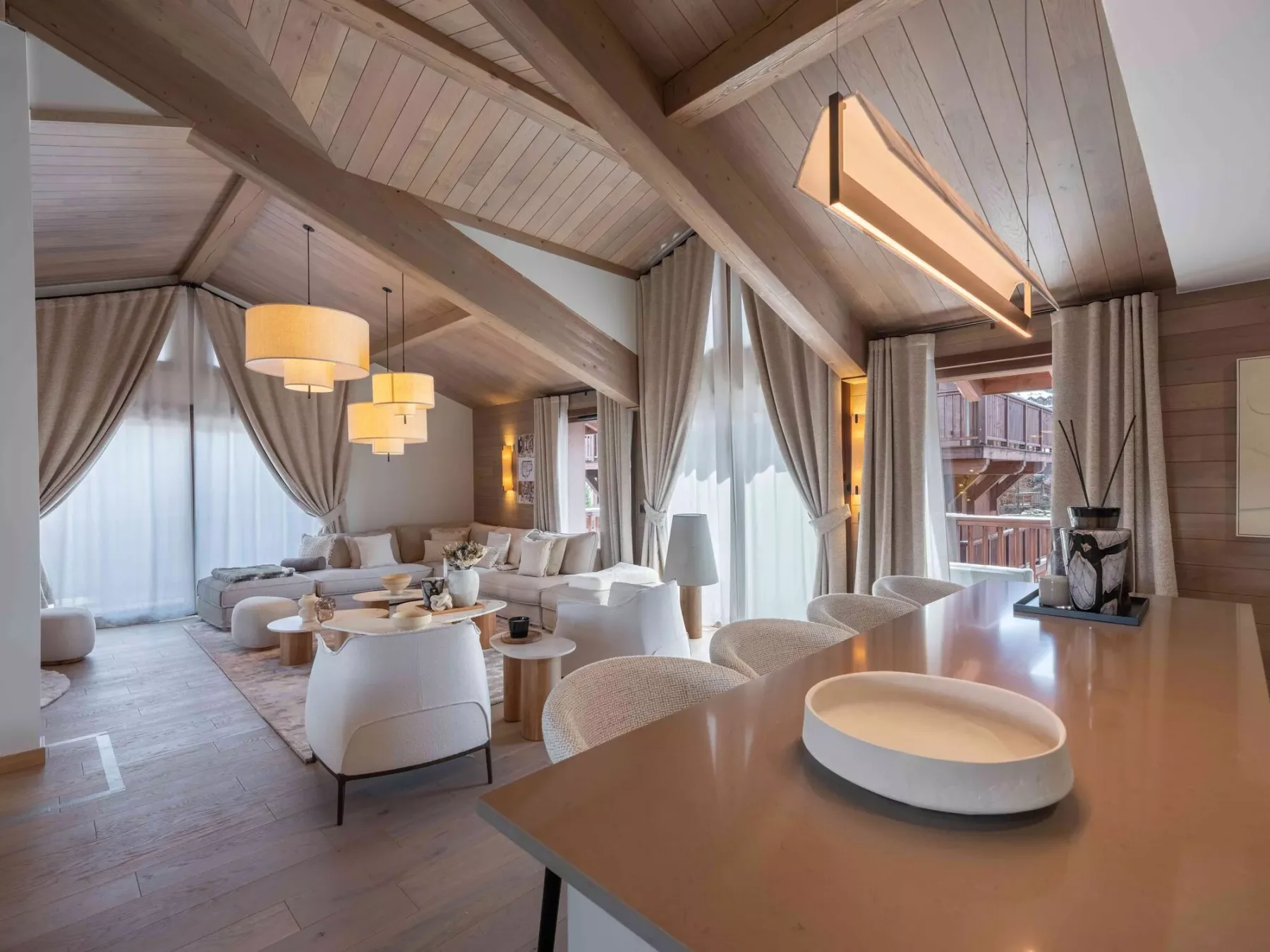 Una sala de estar luminosa con asientos bajo un techo alto revestido de madera.