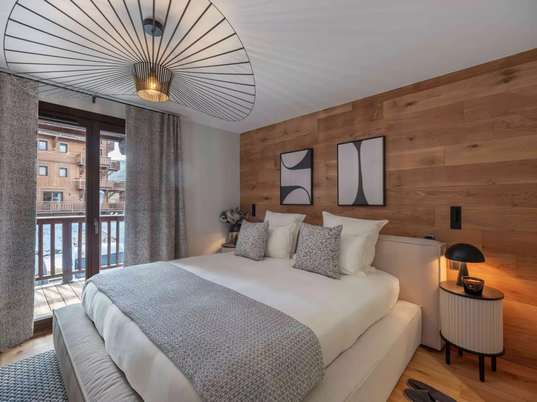 Un dormitorio con una cama, cuadros en la pared y una ventana grande.