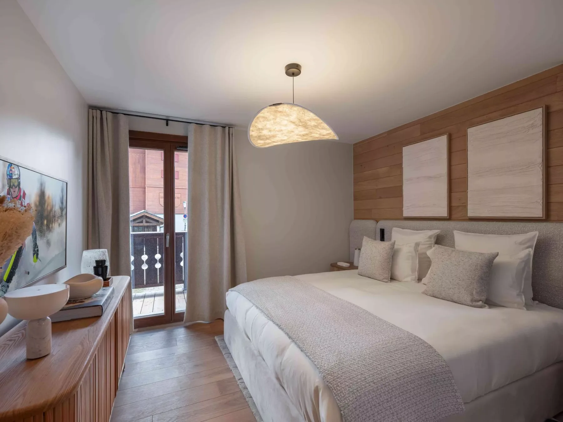 Un dormitorio con una cama grande, una pared revestida de madera y puertas al balcón.