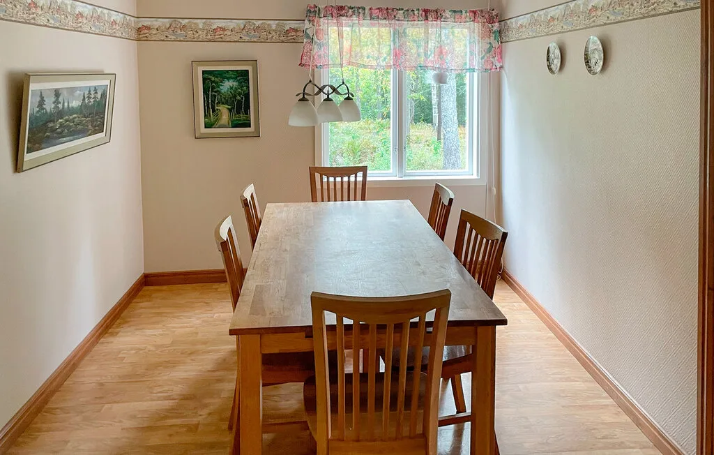 Un comedor con una mesa de madera y sillas junto a una ventana.