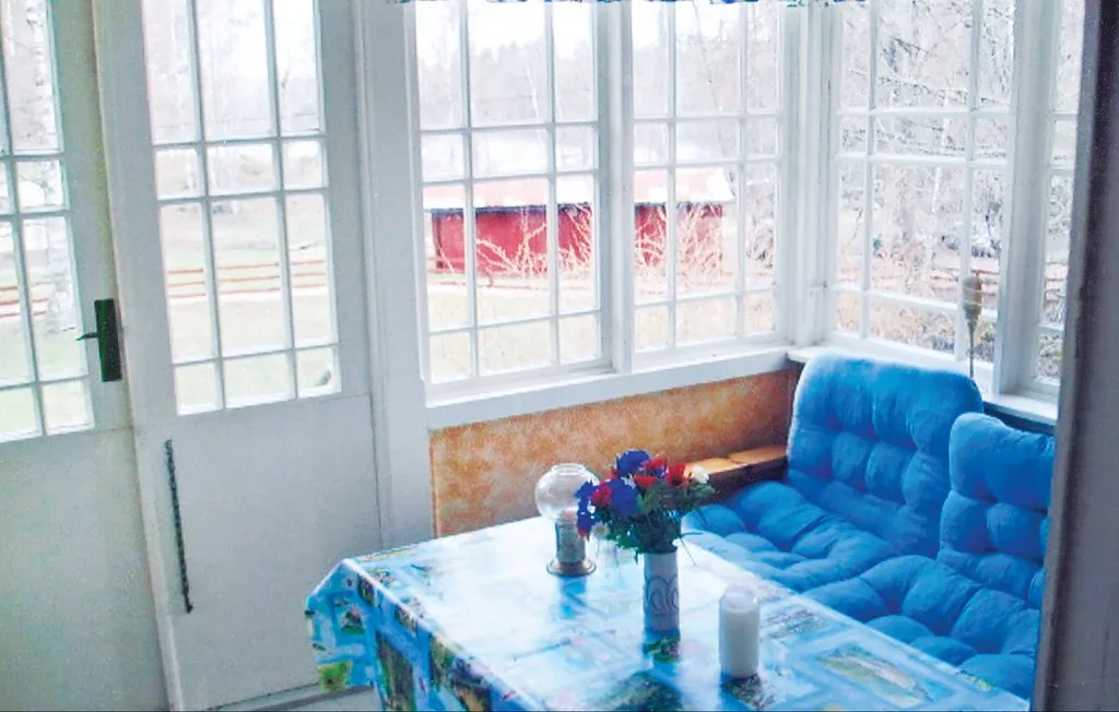 Un solárium con asientos azules y una mesa junto a grandes ventanas.