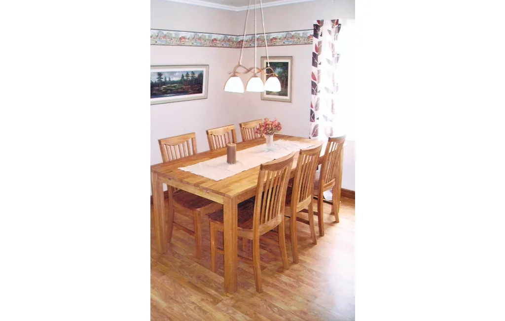 Una mesa de comedor de madera con sillas está bajo lámparas colgantes en un comedor luminoso.