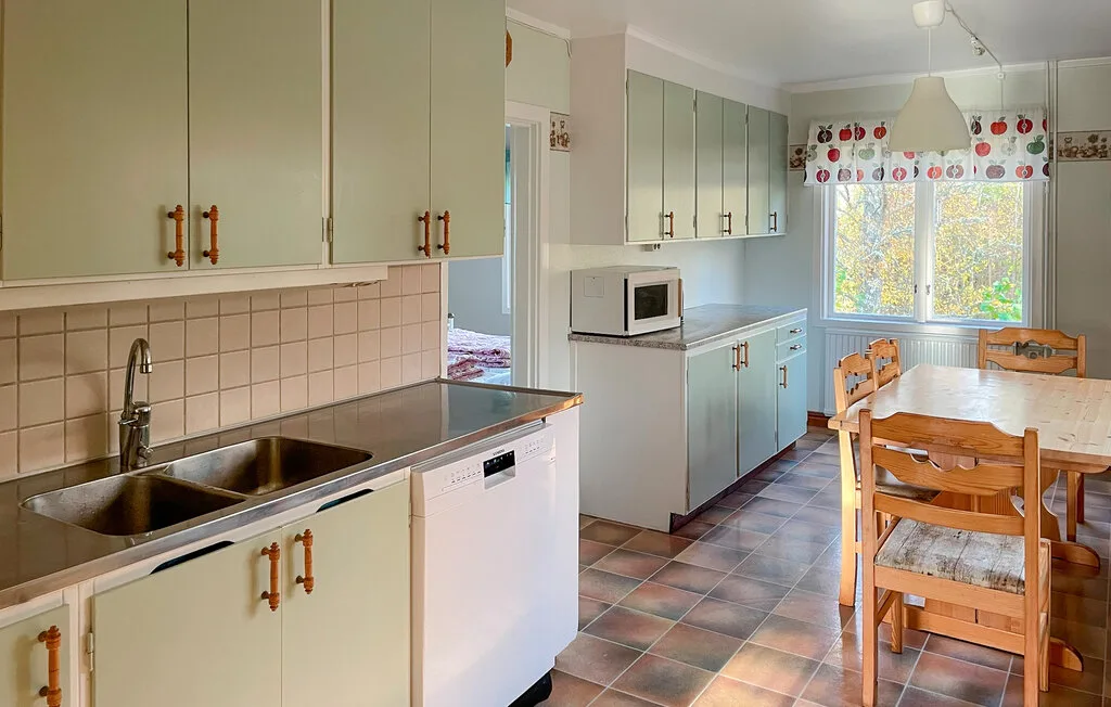 Una luminosa cocina con comedor, gabinetes claros, un fregadero y una mesa de madera.