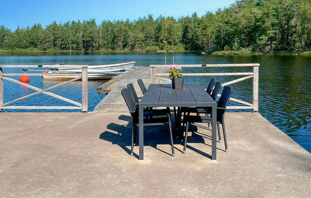 Una terraza junto al lago tiene una mesa y sillas al aire libre junto al agua.