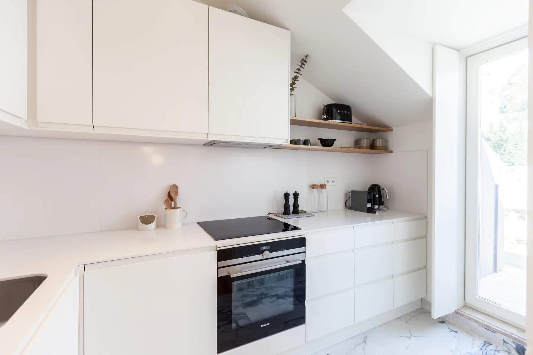 A bright modern kitchen with white cabinets and a built-in oven.