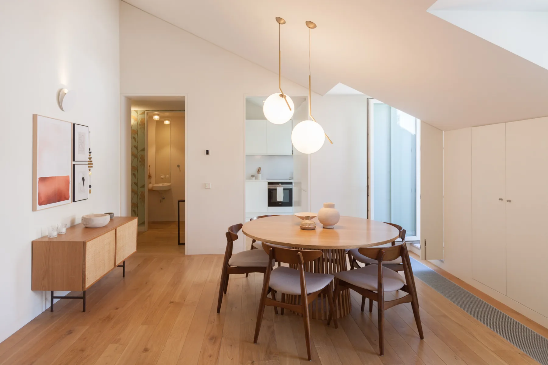 A dining area with a round table sits beside the open kitchen.