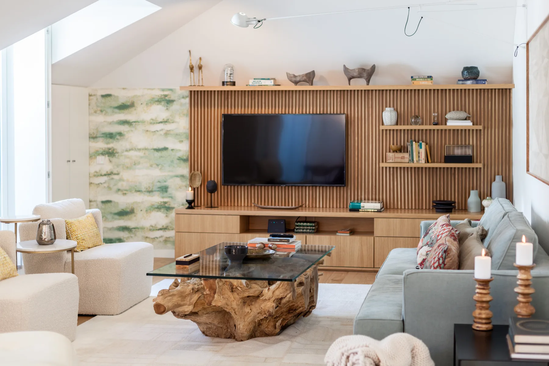 A bright living room features a television wall and a glass coffee table.