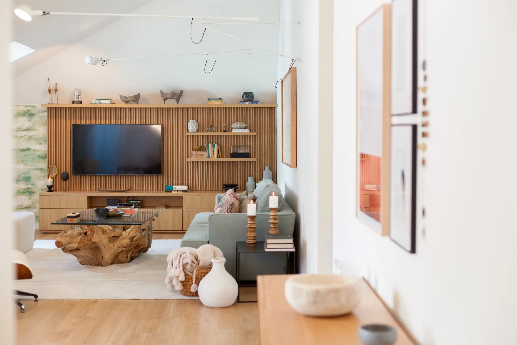 A bright living room with a television and wooden shelving.