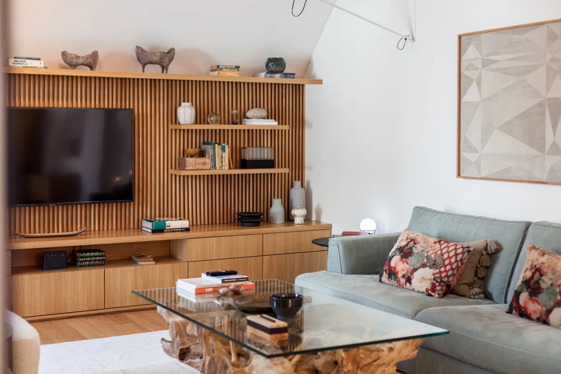 Living room with a television, wood shelving, and a glass coffee table.