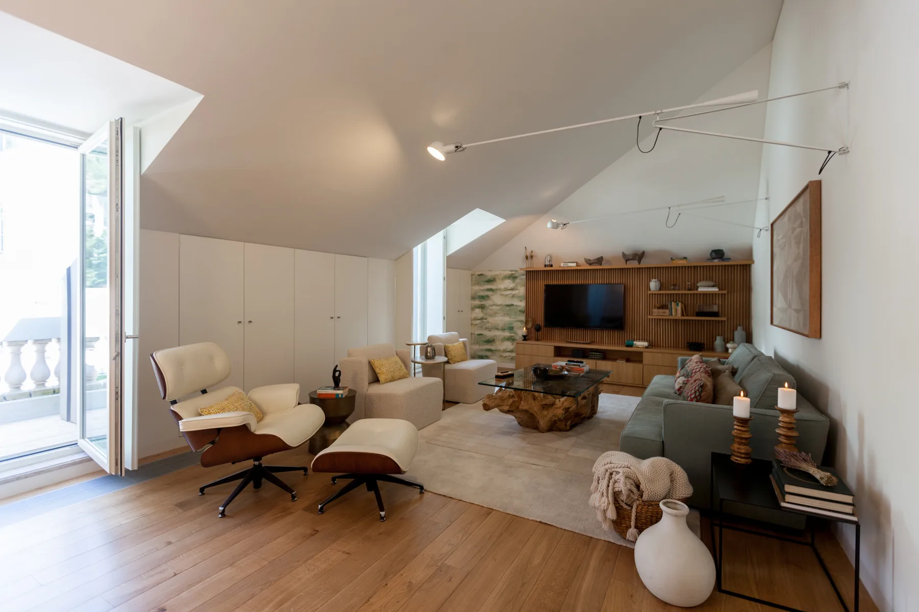 A living room with seating, a television, and an open balcony door.