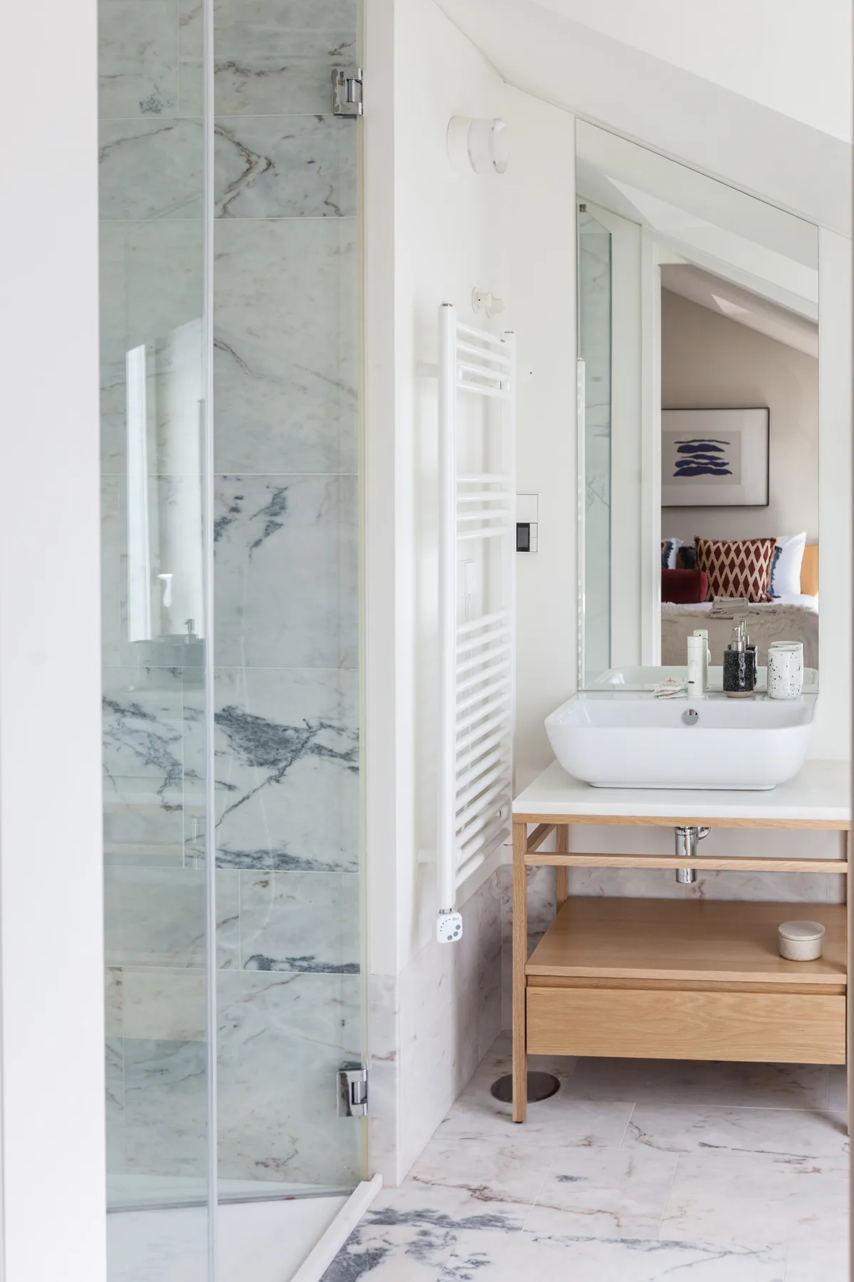 A bathroom with a glass shower and a vanity beneath a large mirror.