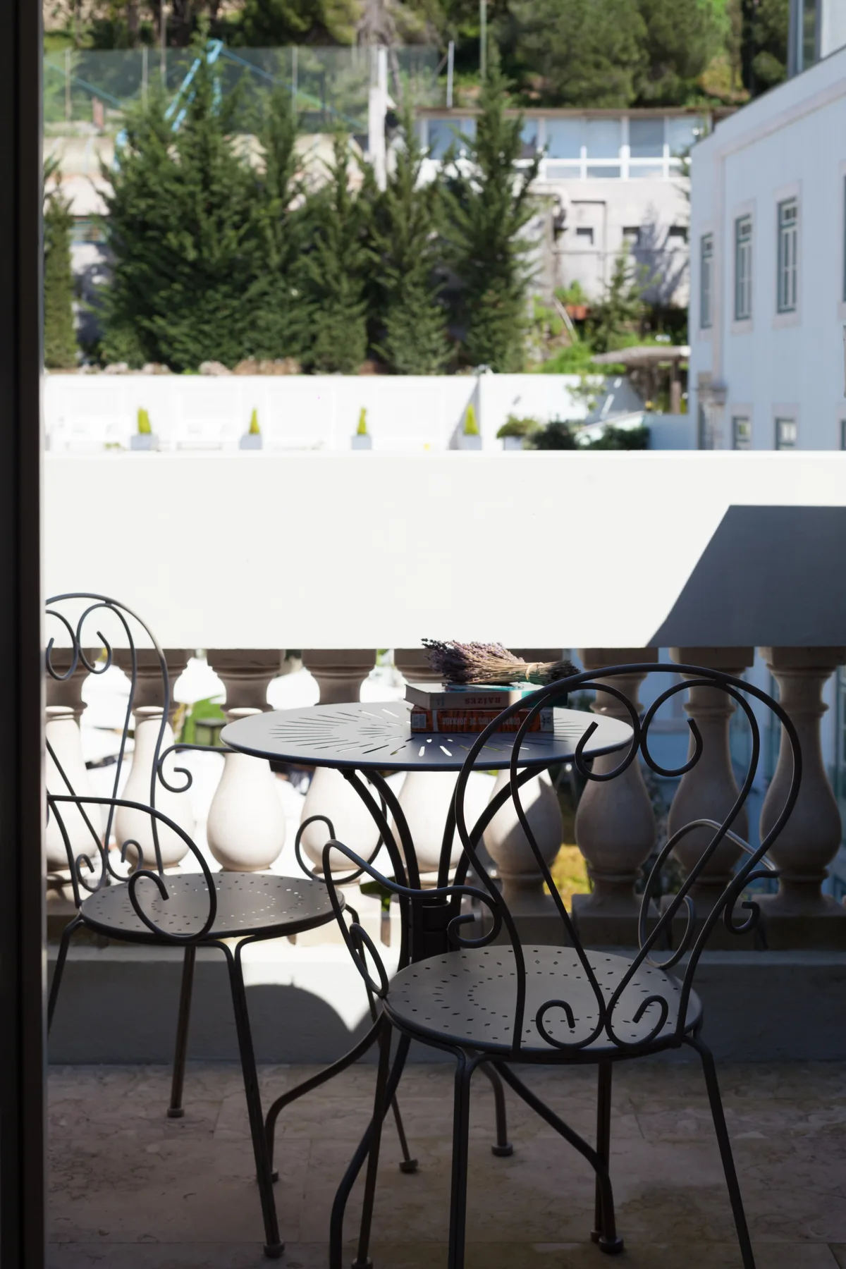 A balcony seating area with a small table and neighboring buildings beyond the railing.