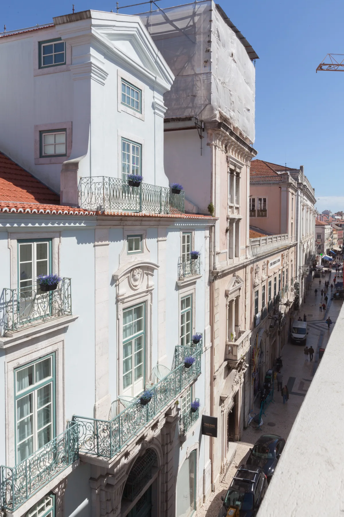 A sunlit city street lined with historic buildings and wrought-iron balconies.