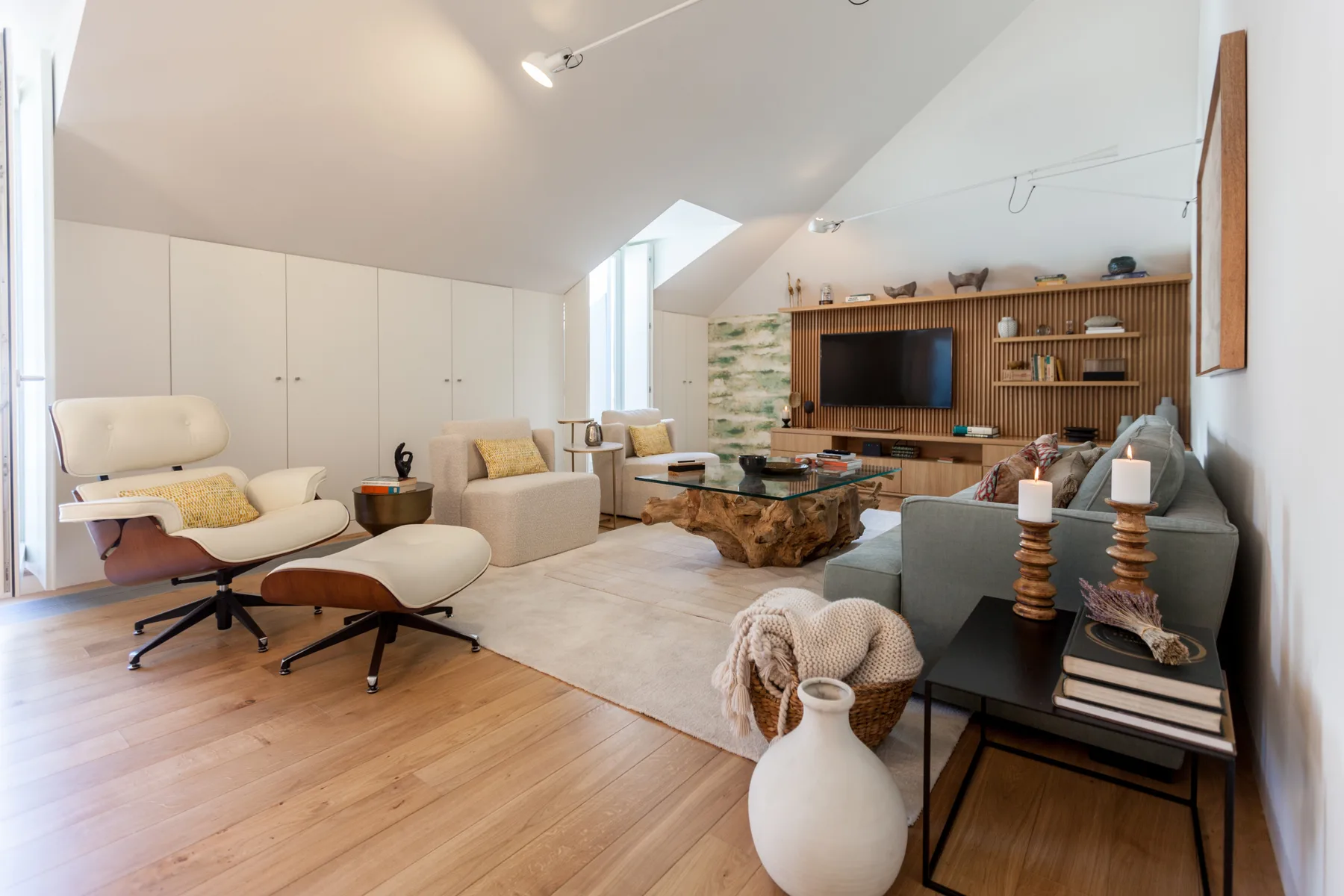 A bright living room with seating around a wooden coffee table and a wall-mounted television.