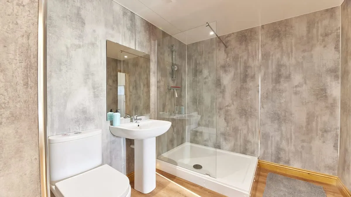 A bathroom with a sink, mirror, and shower.