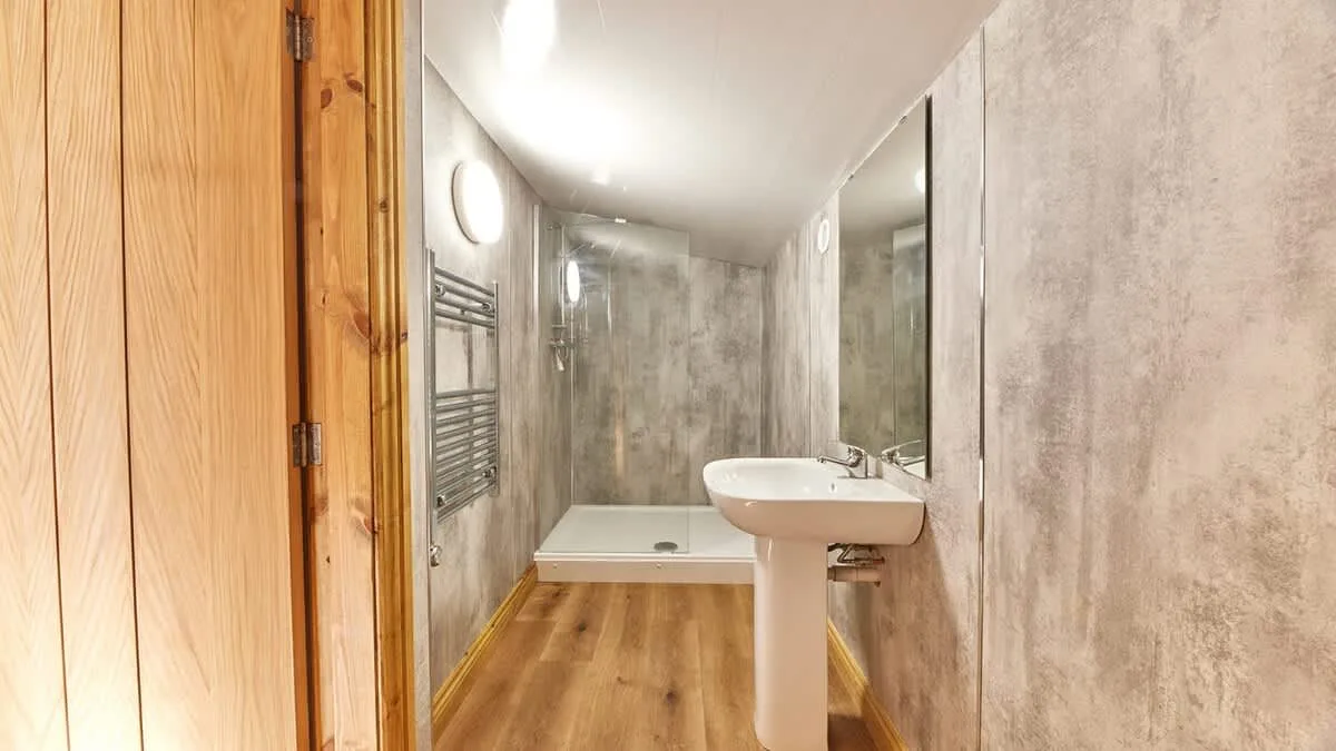 A bathroom with a sink, mirror, and shower at the far end.