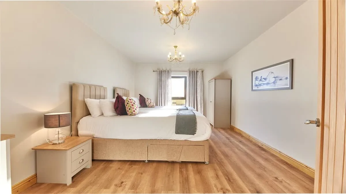 A bedroom with a large bed, bedside table, and window.