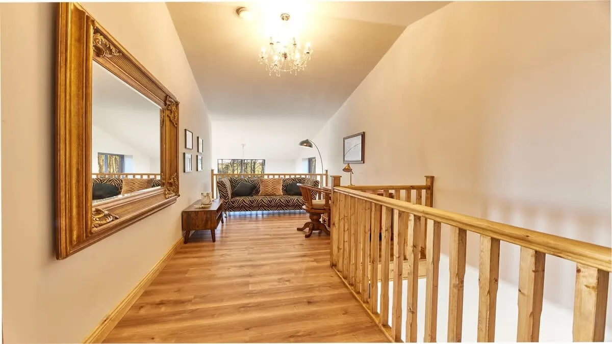An upstairs landing with wood flooring, seating, and a wooden railing.