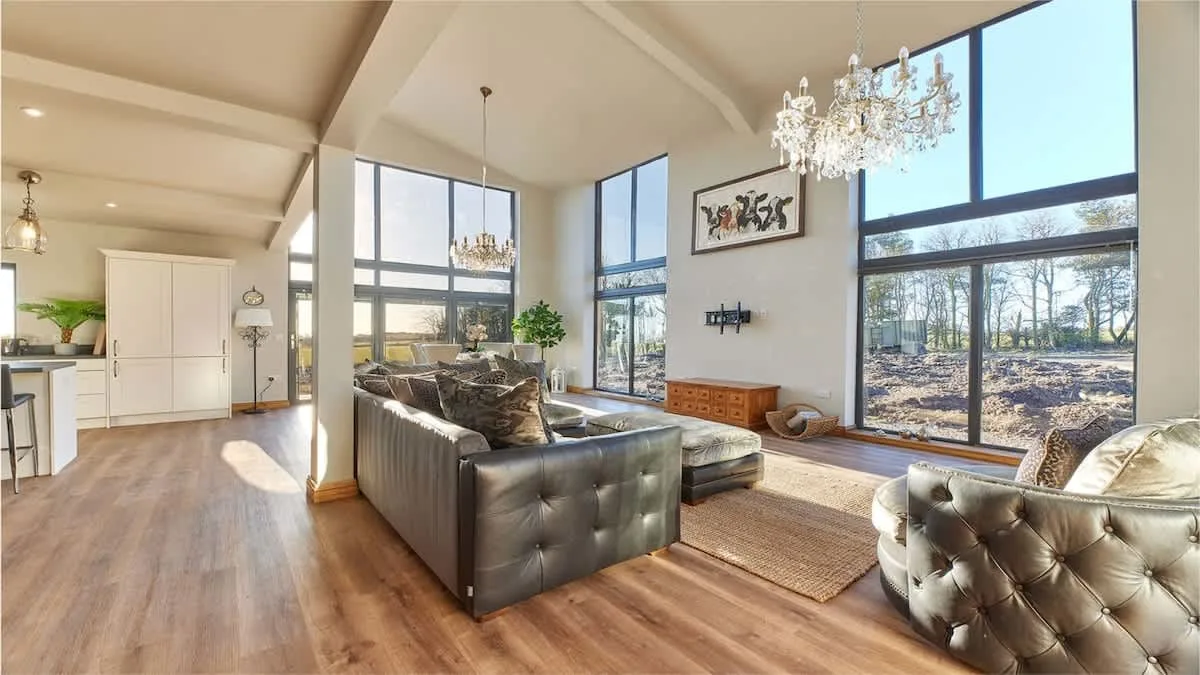 A bright living room with seating, tall windows, and a chandelier.