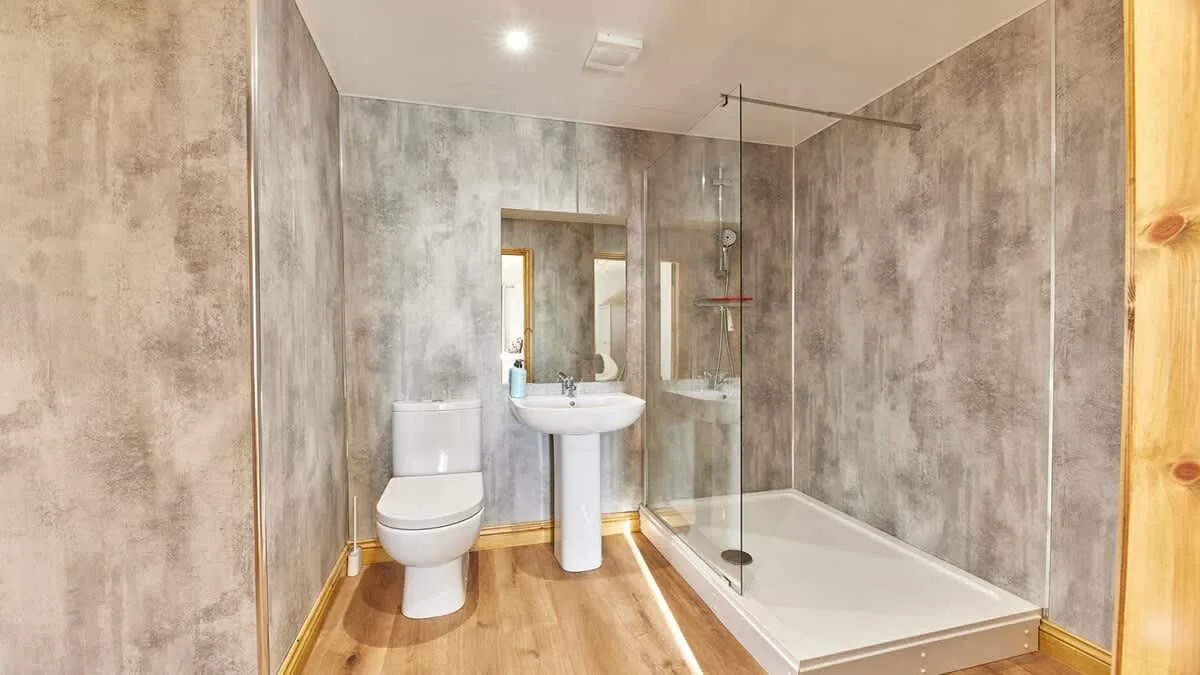 A bathroom with a toilet, sink, and glass shower.
