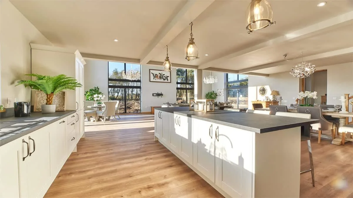 A bright open kitchen with a large island and windows overlooking greenery.