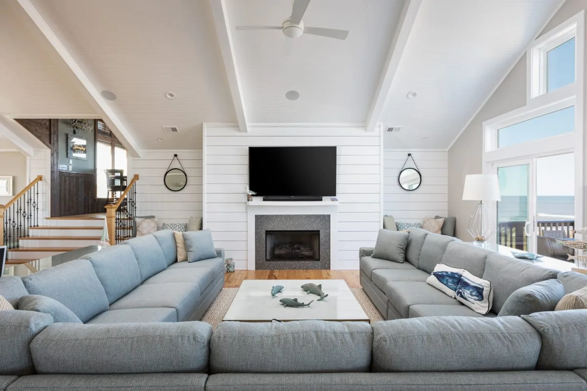 Una sala luminosa con asientos alrededor de una chimenea y un televisor.