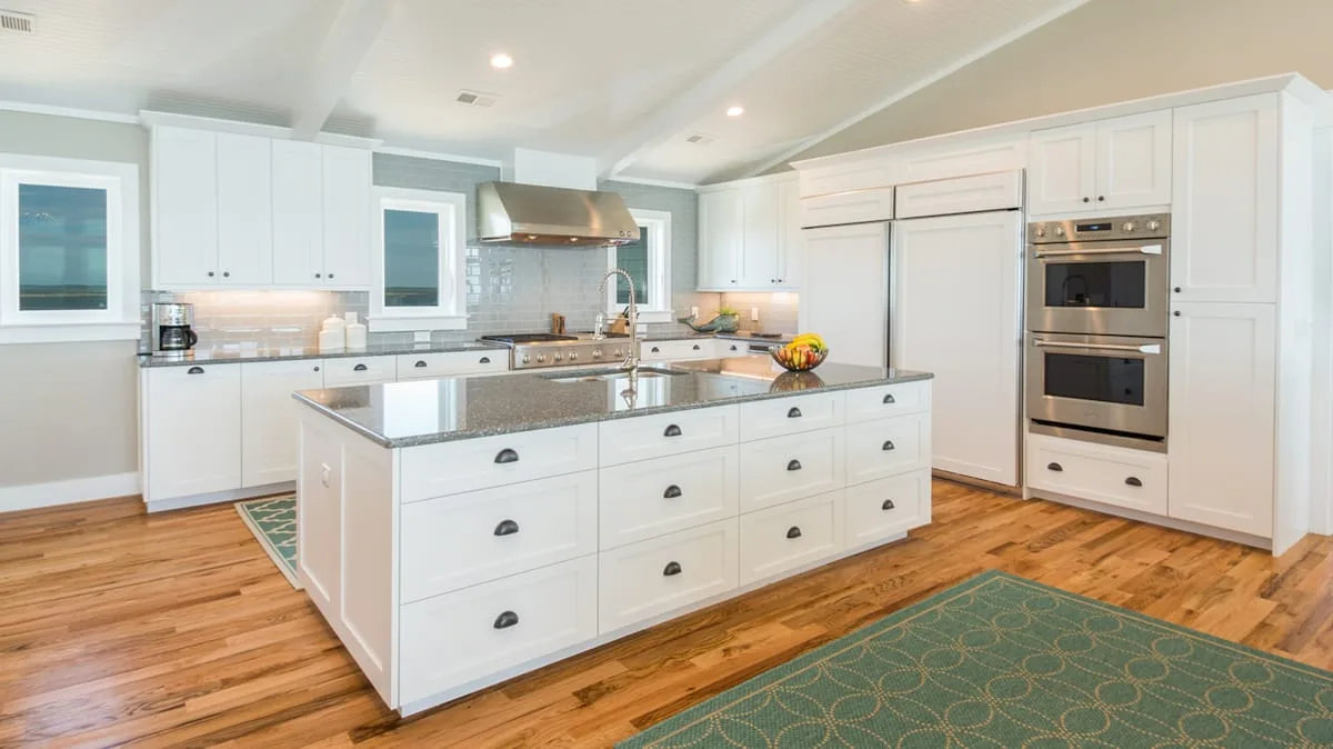 Una cocina luminosa con gabinetes blancos y una gran isla central.