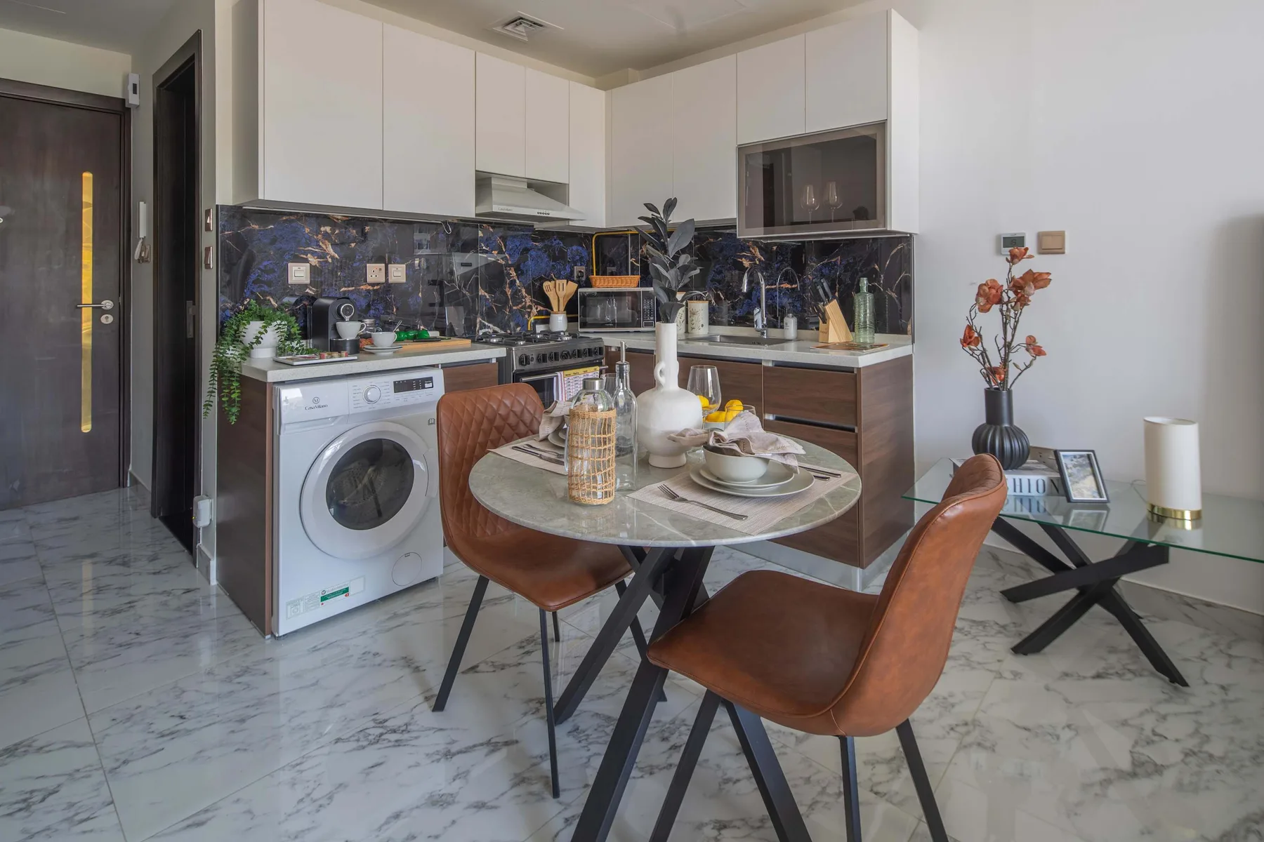 A compact kitchen and dining area with a round table and brown seating.