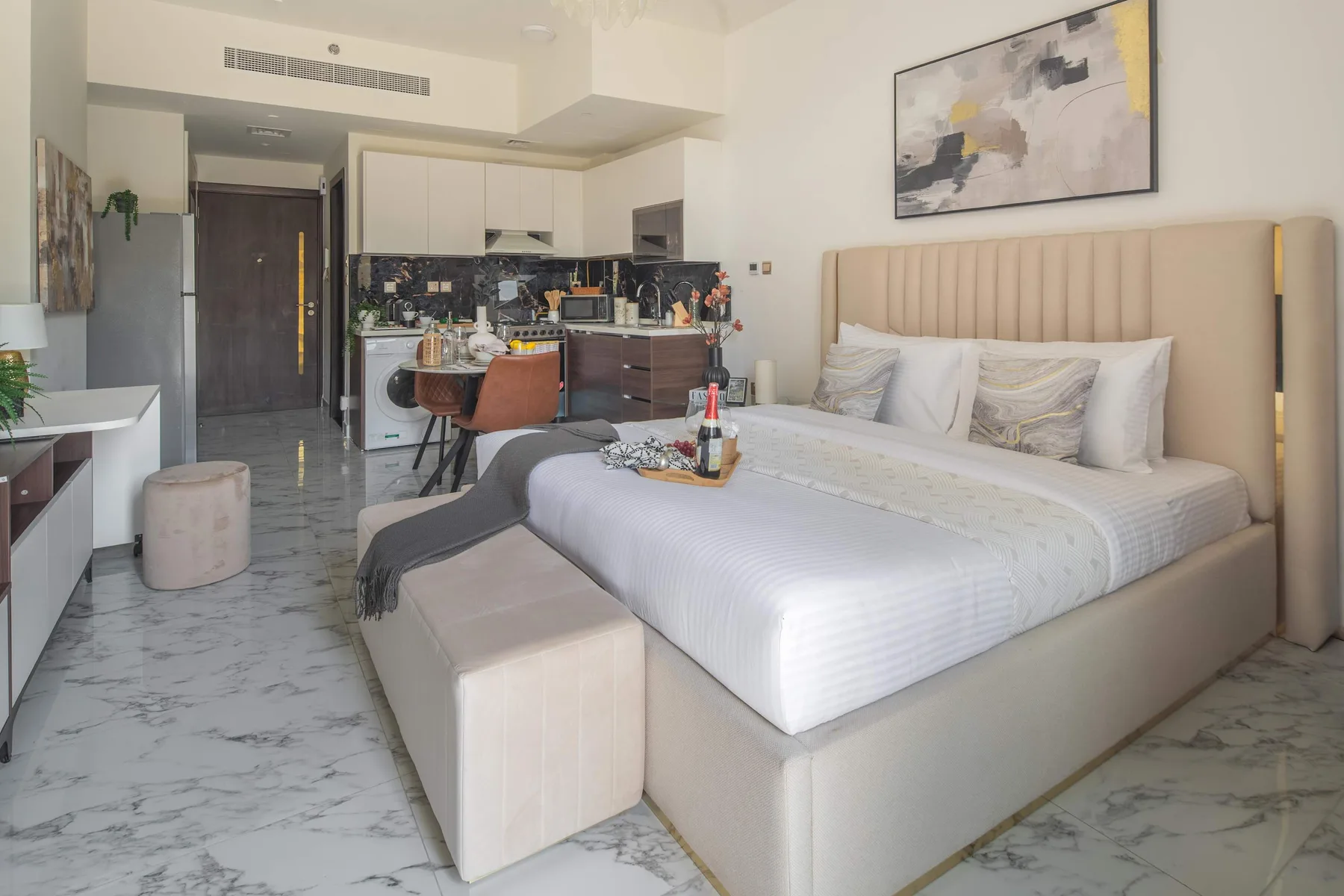A bright bedroom with a large bed and a compact kitchenette.