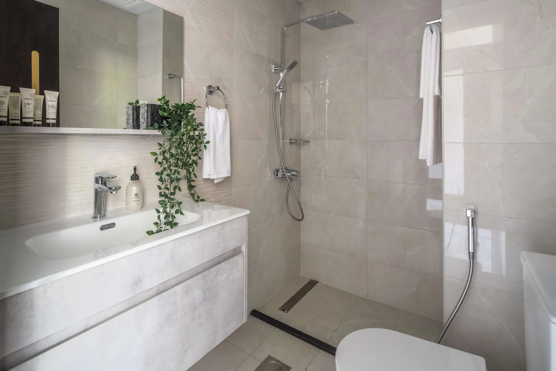 A tiled bathroom with a bathtub, shower, and a leafy plant.