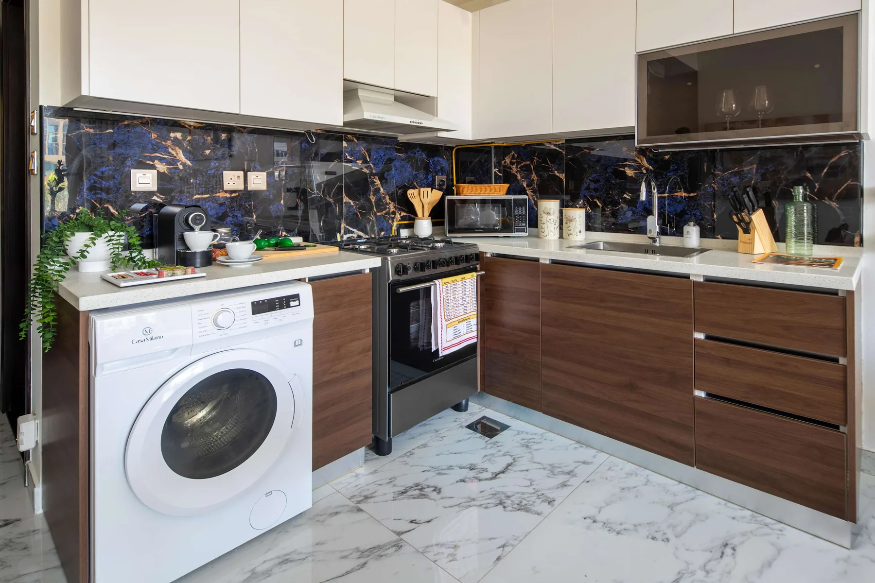 A modern kitchen with dark countertops and a washing machine beneath the counter.