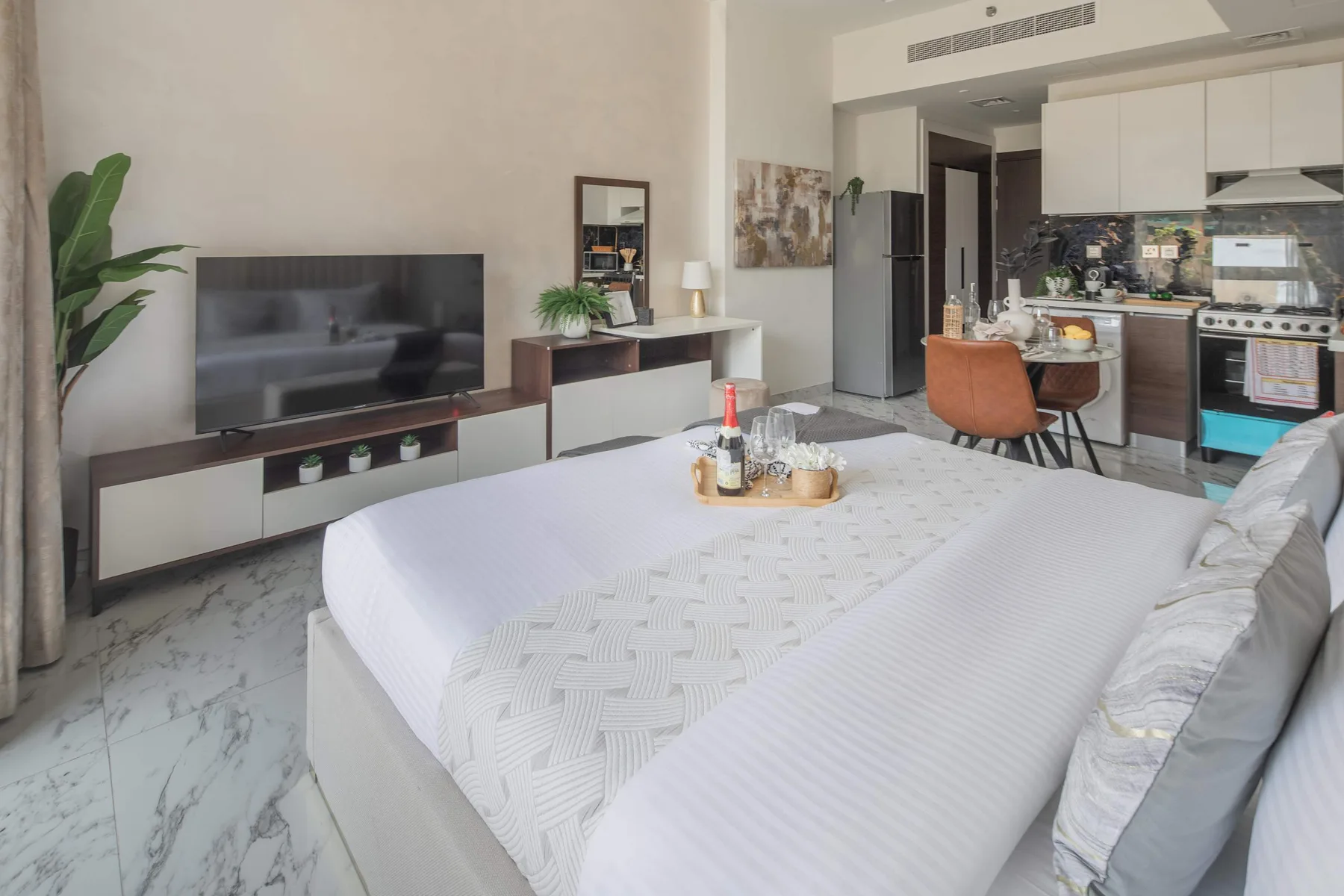A bedroom opens onto a kitchen and dining area, with a large bed in the foreground.