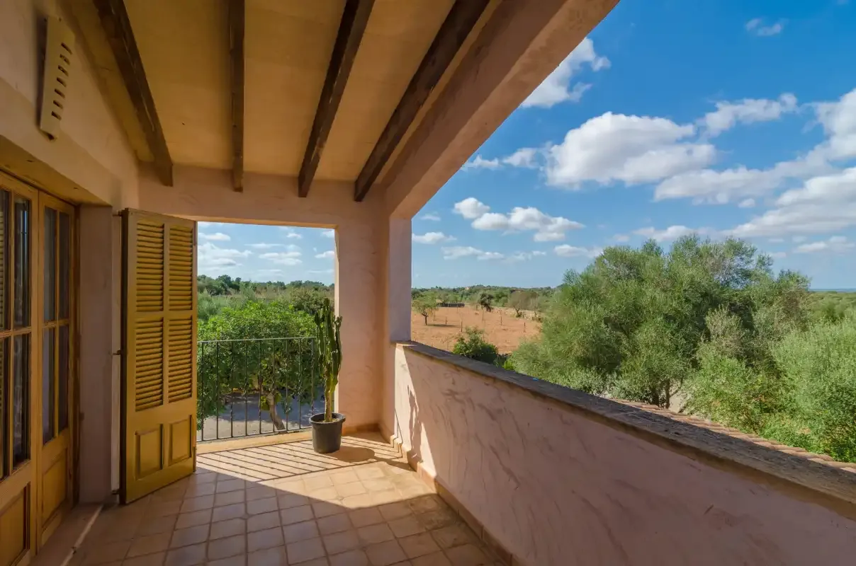 Una terraza cubierta da a campos verdes y árboles.