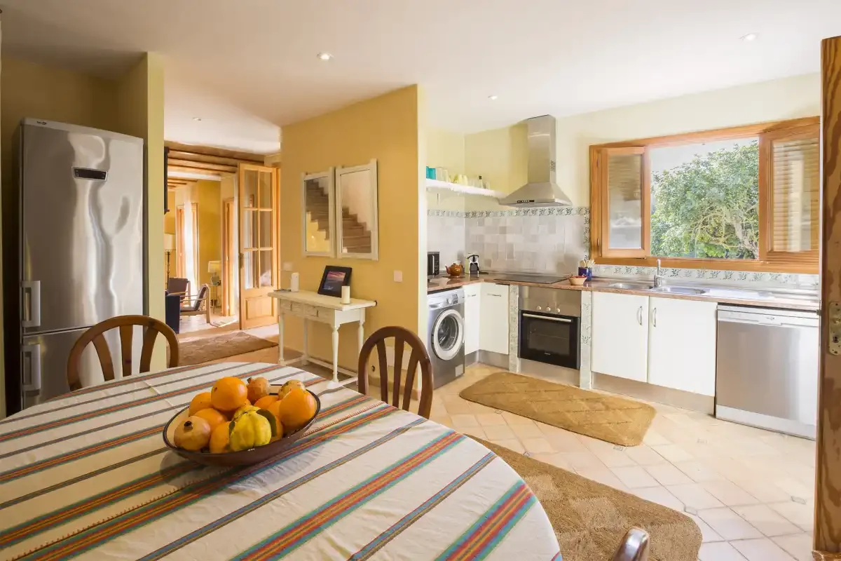 Una cocina y comedor con un mantel a rayas y fruta.