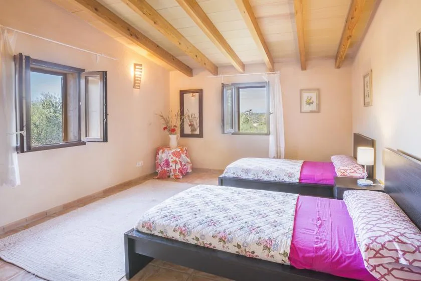 Un dormitorio con dos camas y ventanas abiertas.
